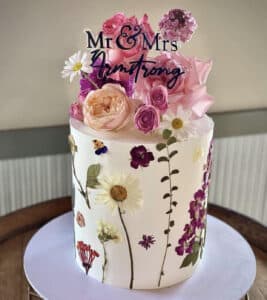 Single tier wedding cake with dried flowers and black cake topper
